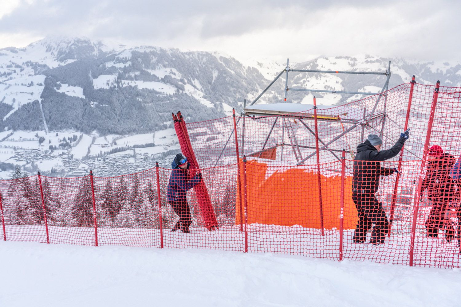 Männer bauen die Fangnetze entlang der Skipiste auf