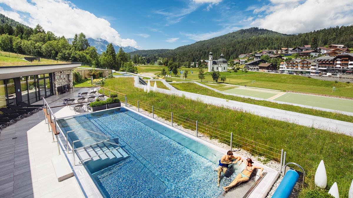 Un’isola di roccia con una fontana al centro, uno scivolo ad acqua di 140 metri, una piscina riscaldata all’aperto, lettini idromassaggio: il centro acquatico di Seefeld riunisce divertimento e relax. Per ancora più benessere, c’è a disposizione un grande reparto sauna., © Region Seefeld, Andre Schönherr